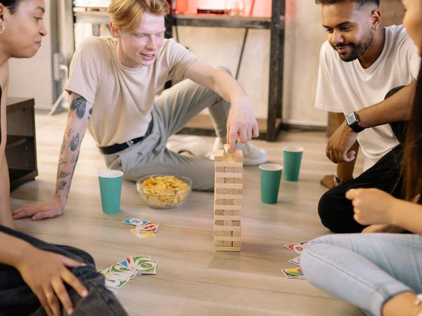 Friends laughing around a table covered in board-game pieces.