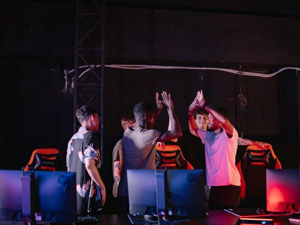 Players high-fiving at their desks after winning a match.