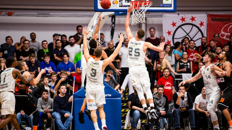 A league basketball match in a packed hall, a player rising to the basket.